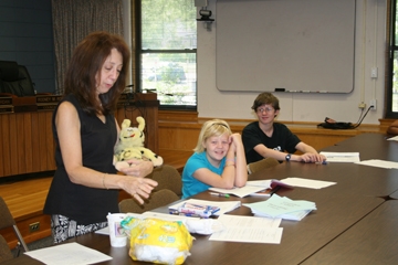 A woman and two young children looking at papers on a table